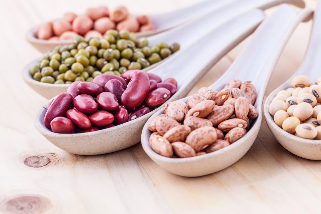 Assortment of beans and lentils in wooden spoon on wooden background. mung bean, groundnut, soybean, red kidney bean , black bean ,red bean and brown pinto beans .